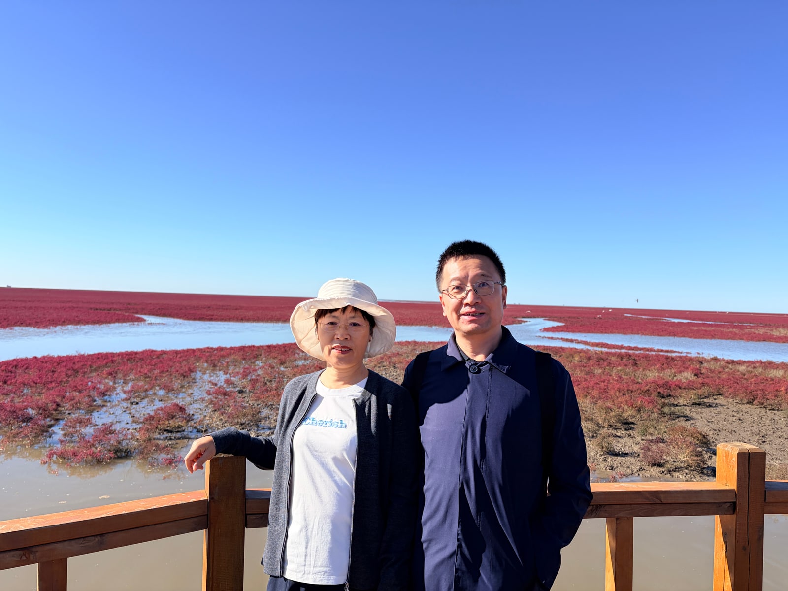 爸爸和妈妈并肩站在红海滩前